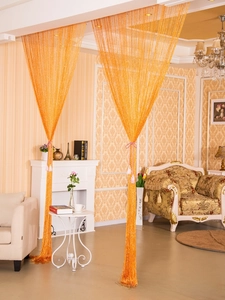 Close-up of vibrant orange tassel string curtain used as a decorative room divider