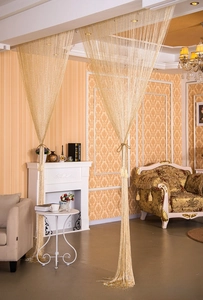 Detail of golden fringe curtain with shimmering metallic threads for room decoration