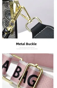 Close-up of golden metal buckle and pink-grey striped fabric strap for crossbody handbag