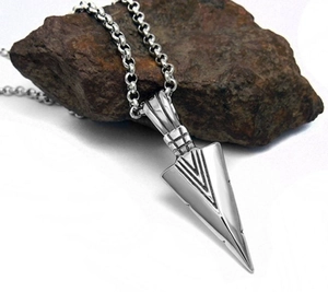 Silver arrow pendant necklace with keel chain displayed on a textured dark rock background