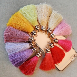 Detailed view of colorful silky tassels with metallic gold caps in a circular layout