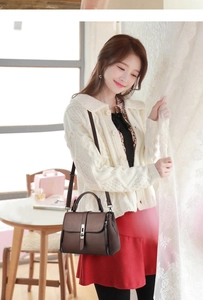 Detail of coffee leather handbag featuring silver metal clasp and premium textured finish