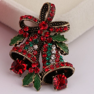 Close-up of Christmas bell brooch with red enamel bow and colorful rhinestones in a gift box