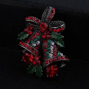 Close-up of Christmas bell brooch with rhinestones and bow on a black leather surface