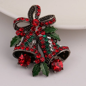 Detail of Christmas bell brooch with red crystals and green enamel holly leaves