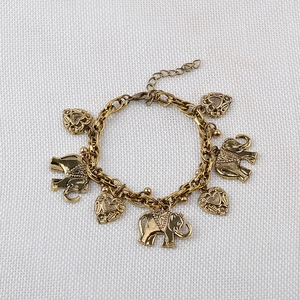 Detailed view of vintage gold elephant and heart charms on a classic link bracelet