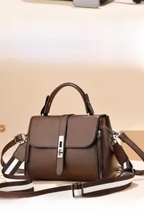 Close-up of a coffee brown leather crossbody bag featuring a striped wide shoulder strap