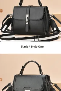 Close-up of black leather crossbody bag with striped strap and gold buckle detail