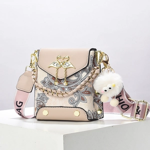 Pink paisley patterned crossbody bag with gold swan buckle and wide strap on white stand