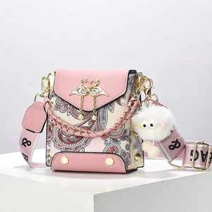 Pink crossbody bag with gold swan buckle, pearl pendant, and paisley pattern accents