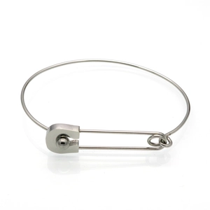 Macro detail of silver safety pin bangle featuring minimalist round bead in titanium steel