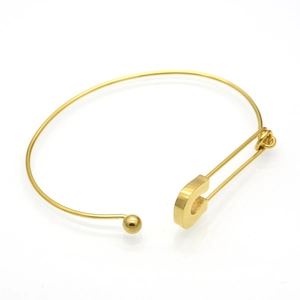 Detailed close-up of a minimalist gold safety pin bracelet in polished titanium steel