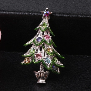 Macro detail of Christmas tree brooch with multicolored rhinestones and green enamel inlay