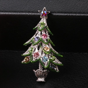 Close-up of a silver Christmas tree brooch with green enamel and multi-colored rhinestones