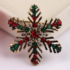 Close-up of snowflake brooch with red, green and white crystals on bronze alloy