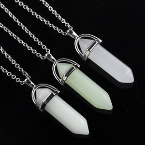 Luminous hexagonal crystal column pendants on silver metal necklaces over dark background