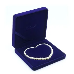 Close-up of a white pearl necklace in a premium dark blue velvet jewelry gift box