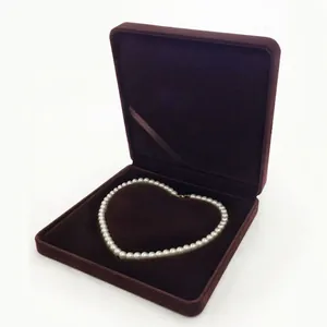 Macro detail of a pearl necklace arranged in a heart shape inside a luxury velvet jewelry box