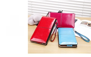 Detailed view of three glossy PU leather long zip wallets in red, pink, and blue with wristlets