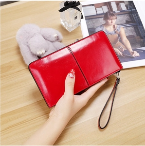 Detail of red patent leather long wallet with smooth texture and sturdy wrist strap