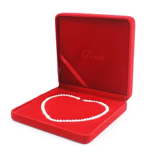 Detail view of a red velvet jewelry box featuring an elegant heart-shaped pearl necklace