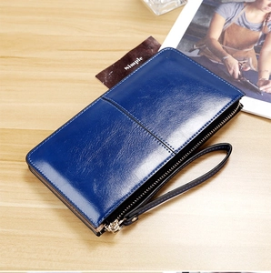 Detail of navy blue glossy patent leather wallet with gold zipper and wrist strap