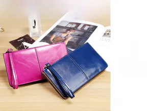 Detail of fuchsia and navy long wallets in glossy leather with wristlet and zipper