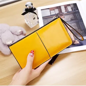 Close-up of a yellow patent leather long wallet for women with zipper and wristlet strap