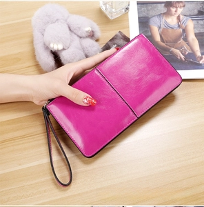 Detail of fuchsia long zipper wallet in glossy leather with wrist strap and hand strap