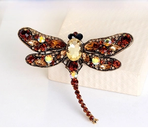 Macro detail of vintage dragonfly brooch featuring amber crystals and bronze alloy base