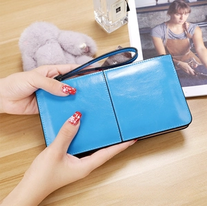 Detail of bright blue long wallet in oily wax leather held against a wooden desk
