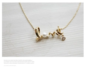 Detail of 18K gold Love script necklace with elegant pearl and sparkling zircon pendant