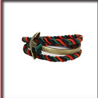 Detail of red, black, and green braided rope bracelet with a bronze anchor clasp