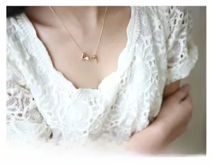 Close-up of golden LOVE letter necklace with a pearl and diamond accent on female neck