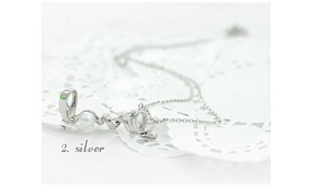 Close-up of silver Love letter pendant featuring a small white pearl on lace background