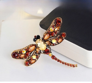 Detail of dragonfly brooch with amber rhinestones and gold alloy on a display stand