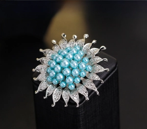 Detailaufnahme der silbernen Sonnenblumen-Brosche mit blauen Perlen und Kristallen