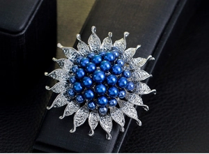 Detailansicht der blauen Perlen-Sonnenblumenbrosche mit Kristallblättern auf schwarzem Leder