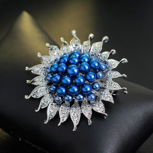 Modische Blumenbrosche mit blauen Perlen und silbernen Blättern auf Schmuckkissen
