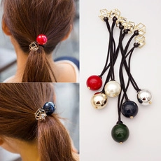 Dettaglio di elastici per capelli colorati con perline rotonde e cubi dorati su fasce nere
