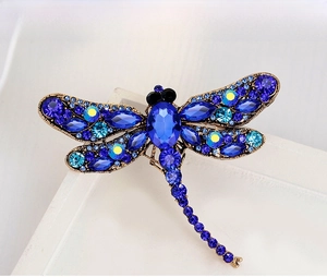 Close-up of vintage dragonfly brooch with blue rhinestones and gold alloy frame