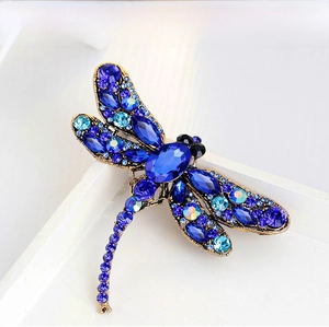 Detailed close-up of a vintage dragonfly brooch with blue crystals and gold metal