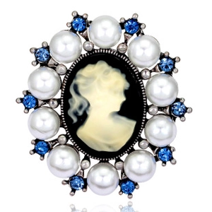 Close-up of vintage cameo brooch featuring white pearls and blue rhinestones details