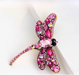 Macro shot of a vintage gold dragonfly brooch with pink crystals and intricate rhinestones