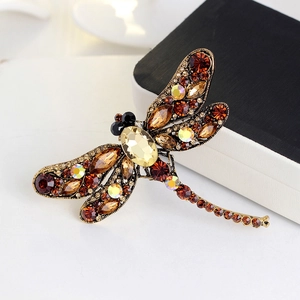 Vintage dragonfly brooch with amber crystals on bronze metal base over white background