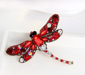 Macro detail of vintage dragonfly brooch with red rhinestones and golden alloy base