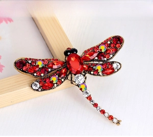 Detail of dragonfly brooch with vintage gold finish and red rhinestone embellishments