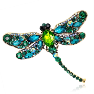 Vintage dragonfly brooch with colorful rhinestones on gold metal and a white background