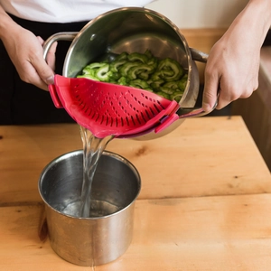 Silicone pot strainer with metal clips filtering boiling water from a cooking pot