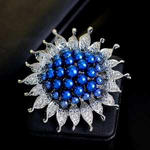 Eleganter silberner Sonnenblumen-Brosche mit tiefblauen Perlen auf schwarzem Untergrund